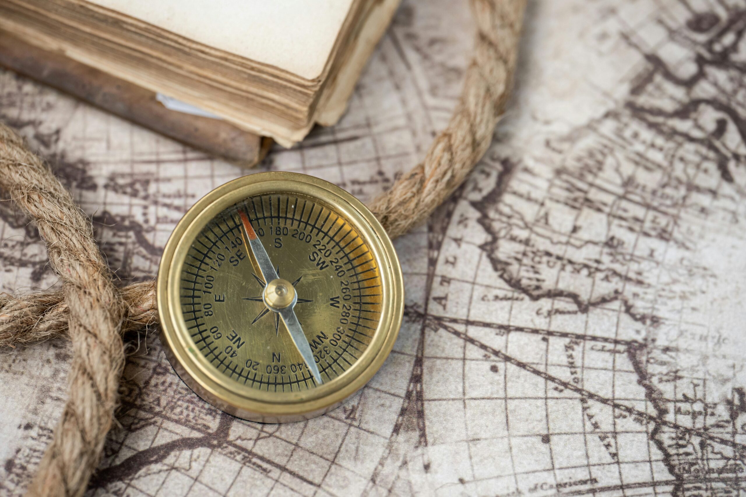 A close-up of a vintage compass on an antique world map, depicting navigation history.